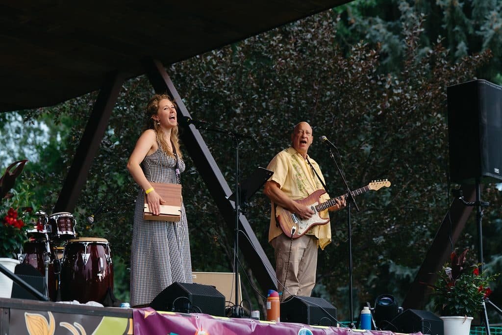 Stefan playing electric guitar beside a singer on a covered outdoor stage